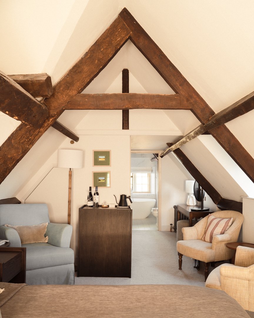 Interior of bedroom at Hyll Hotel with exposed beams and warm light. 